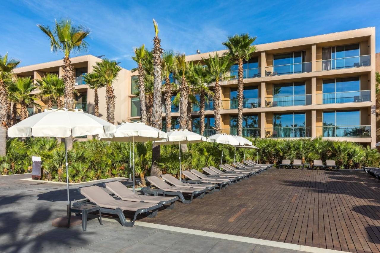 Ap Lago Montargil - Conference & Spa المظهر الخارجي الصورة The photo shows a modern resort or hotel area featuring several lounge chairs lined up on a wooden deck. Each lounge chair is paired with a white umbrella, providing shade. In the background, there are palm trees, which add to the tropical atmosphere
