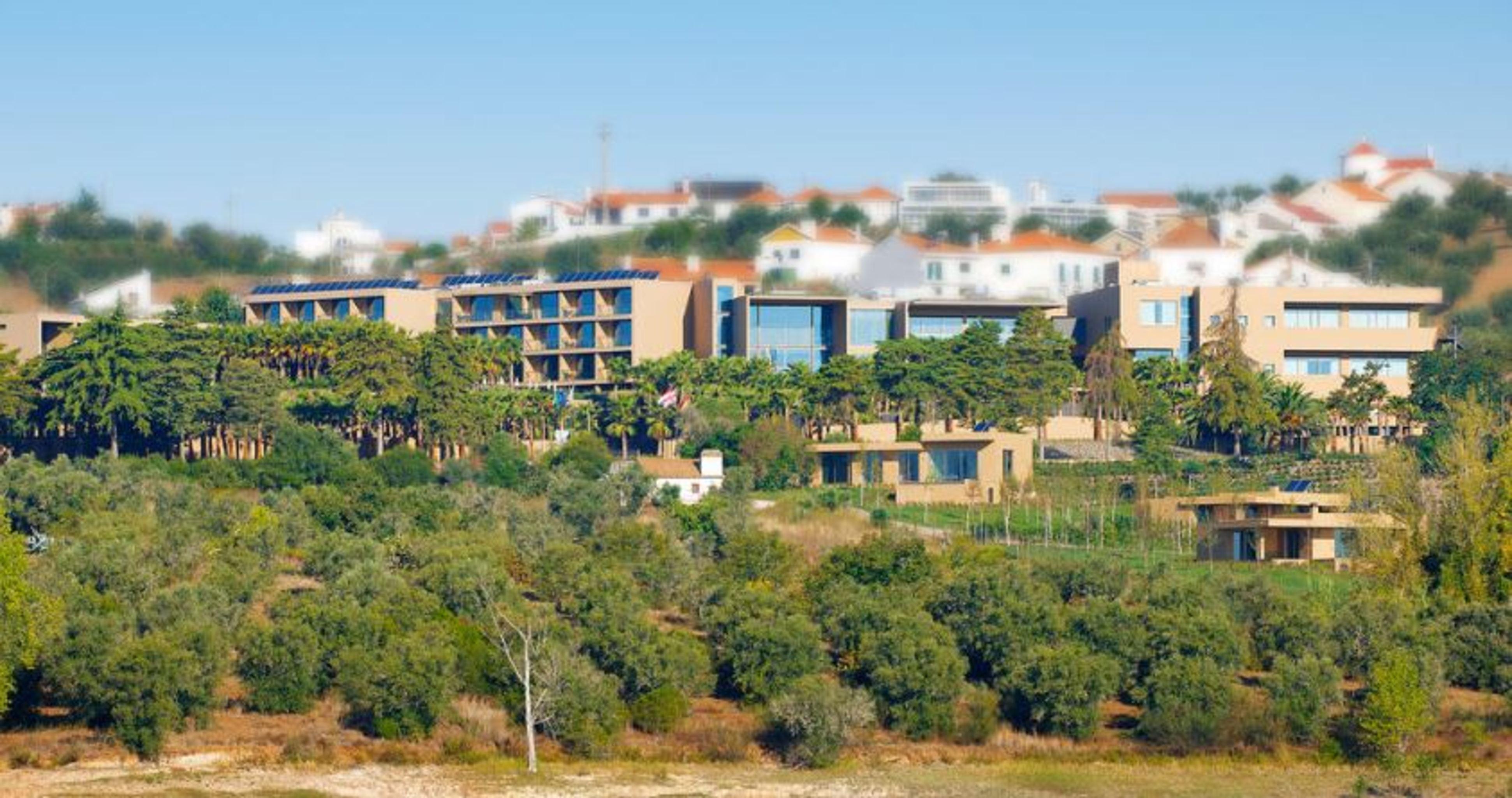 Ap Lago Montargil - Conference & Spa المظهر الخارجي الصورة The photo shows a hillside view of a modern resort or hotel complex surrounded by greenery. The buildings are designed with a blend of contemporary architecture and natural elements, featuring wooden accents, large windows, and terraces. In the backg