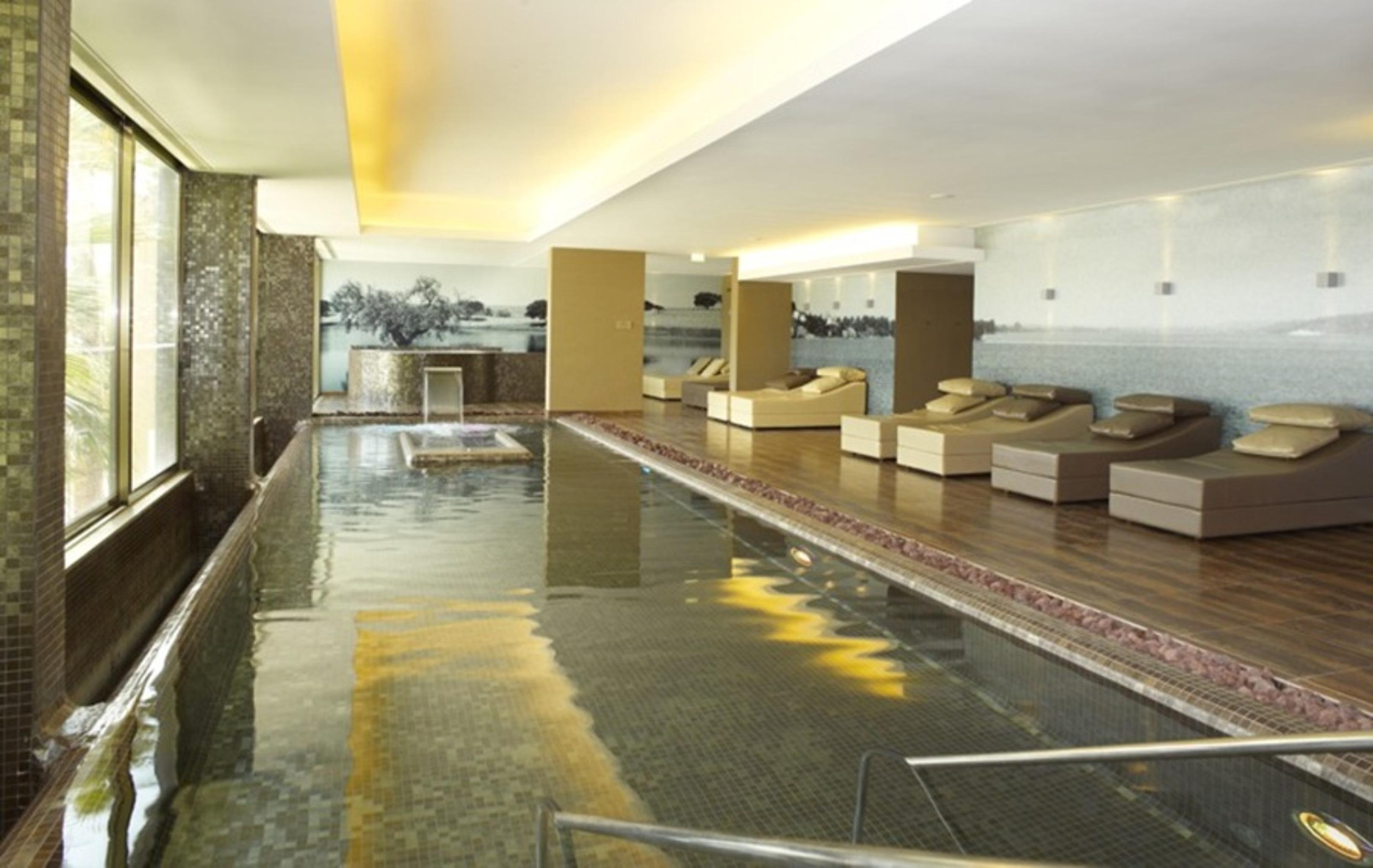 Ap Lago Montargil - Conference & Spa المظهر الخارجي الصورة The photo shows a modern, serene spa environment. There is a swimming pool with calm water, reflecting the surrounding decor. Along the sides, there are several comfortable lounge chairs arranged, perfect for relaxation. Large windows allow natural l