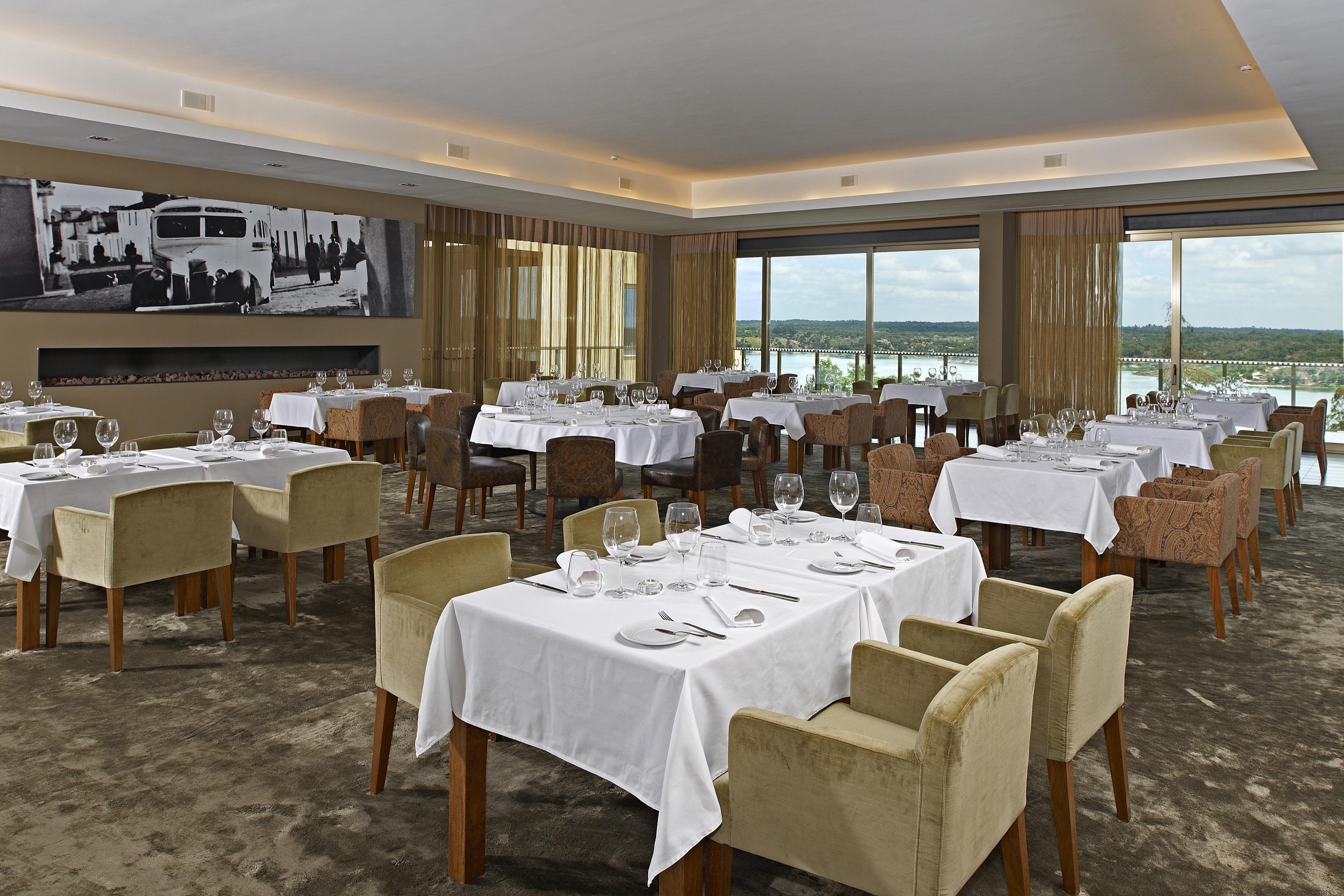 Ap Lago Montargil - Conference & Spa المظهر الخارجي الصورة The photo shows an elegant restaurant interior featuring neatly arranged tables with white tablecloths. Each table is set with plates, cutlery, and glasses. The seating includes a mix of upholstered chairs in different colors—some light and others da